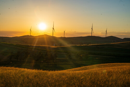 Wind Turbines Bathed in Golden Sunset Glow.