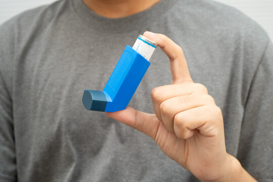 Asthma and chronic obstructive pulmonary disease COPD, Asian young man using metered dose inhaler MDI.