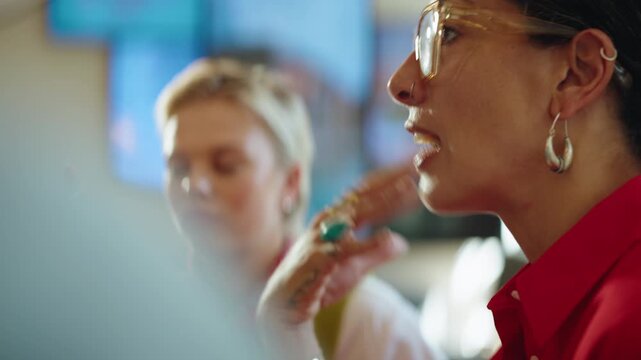 Gesturing women exchange feedback during a business meeting in a coworking cafe, showing collaboration, discussion, communication, and startup teamwork in a flexible workplace.
