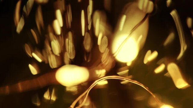 Macro shot of shimmering golden bokeh lights reflecting through textured glass with warm ambient illumination.