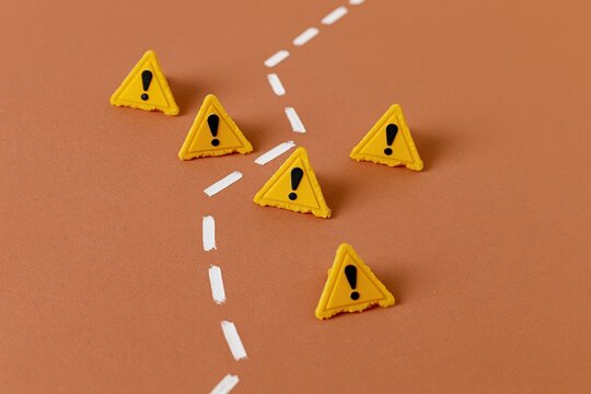 The warning triangles along a dashed path on a brown surface