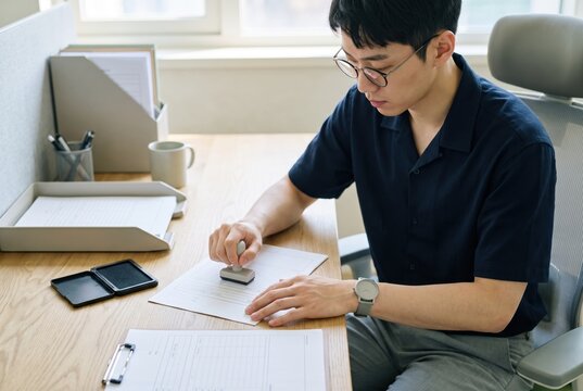 Generative AI, Asian man stamping an official document at an office desk