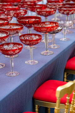 Major preparations for grand celebration, festive table setting in restaurant with rows of glasses, red crystal champagne coupes on table at luxury wedding arrangement or anniversary ceremony.