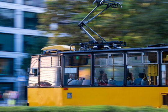 Yellow tram with passengers and motion blur moves through urban Wola, Warsaw, Poland combining transport with movement across the frame.