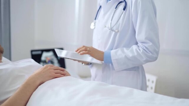 Doctor consulting patient with digital tablet in hospital room. Healthcare professional providing care