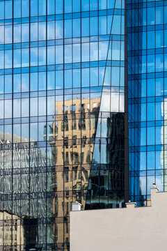 Blue glass facade with reflections and windows forming abstract architecture and geometry in Wola, Warsaw, Poland across the full frame.