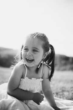 Laughing Little Girl Sitting Outdoors In Sunlight Black And White Candid Portrait