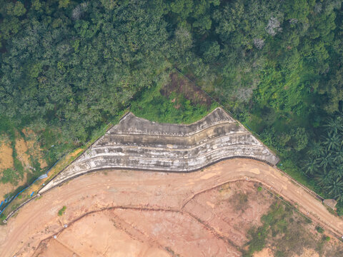Aerial view of slope stabilization anchoring on a hillside with exposed earth and surrounding forest in Bukit Mertajam, Penang, Malaysia.