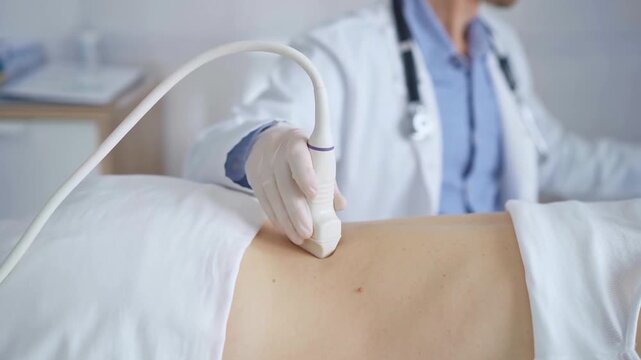 Doctor man wearing white protective gloves is using ultrasound equipment on the back of a patient, woman. Physician analyzing the results on a monitor in the background. Medicine