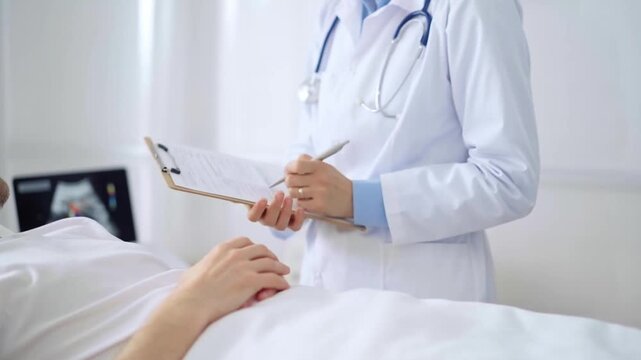 Female doctor writing medical report of patient lying in bed in hospital