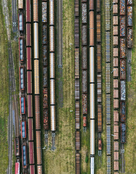 Aerial view of freight trains parked on parallel tracks in a railway yard loaded with logs and scrap metal in Saalfeld, Thuringia, Germany.