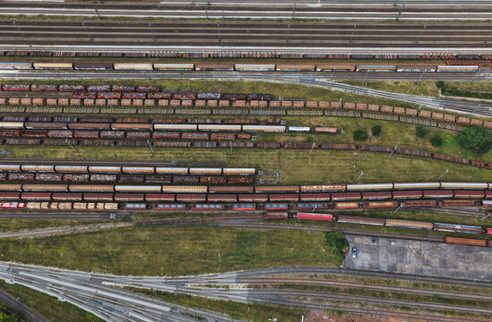 Aerial view of a busy railway yard featuring numerous parallel tracks filled with various freight train cars, surrounded by grassy areas and industrial infrastructure in Saalfeld, Thuringia, Germany.