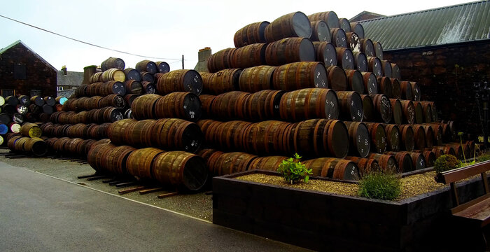 Aerial view of Bruichladdich Distillery with stacks of wooden whisky barrels stored outdoors in Bruichladdich, Scotland, United Kingdom.