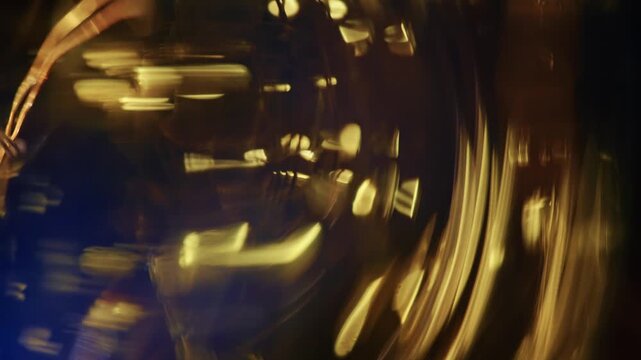 Macro shot of swirling golden light streaks and glass refraction with subtle violet flare against a dark background.