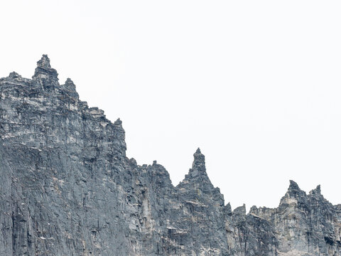 Aerial view of the jagged, steep rock faces of the Troll Wall mountain range with sharp peaks and rugged stone textures in Andalsnes, More og Romsdal, Norway.