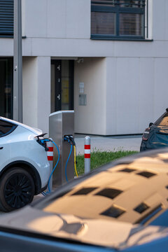 Electric car charging beside a modern building in Vienna, Austria, with urban architecture and reflection visible around the parking area.