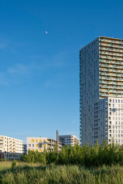 Highrise tower rises above grass and buildings in Vienna, Austria, combining vertical architecture with an urban landscape beneath the sky.