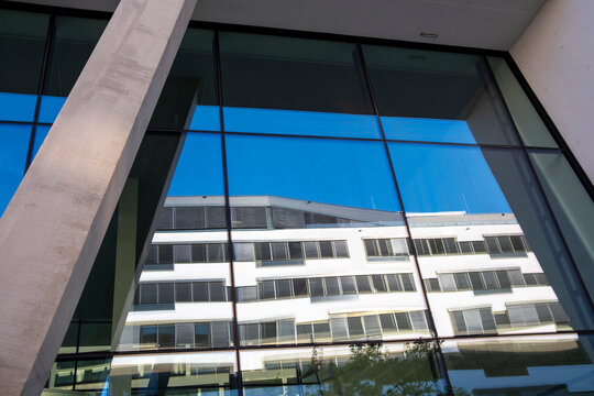Modern architecture with reflection in blue glass windows creates geometry across the facade of a building in Vienna, Austria, from edge to edge.