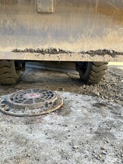 Heavy earthmoving equipment working on new development. Close view of dozer blade grading ground near utility access point. Industrial background. Manhole © grooveisintheheart