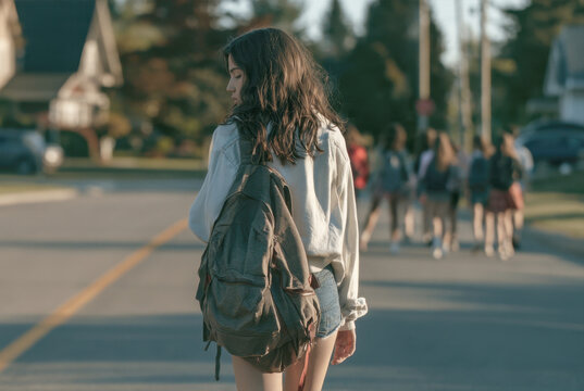 young student girl walking along sunny suburban street with backpack on road going home from high school education back to school campus outdoor lifestyle teenage back view casual clothes walking
