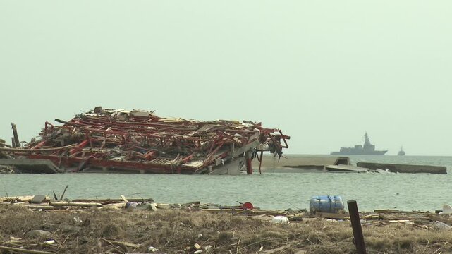 Destroyed Building In Flood Waters With Navy Ship Offshore In Aftermath Of Tsunami In Japan