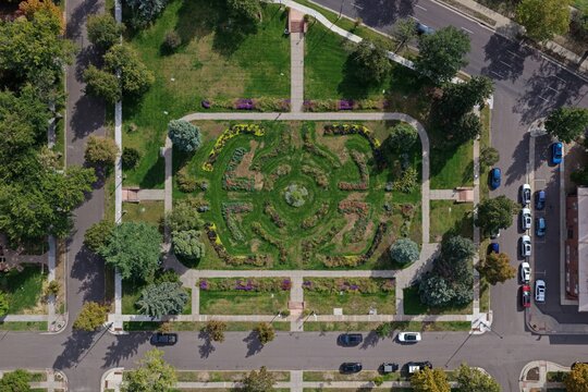 Aerial view of a symmetrical garden park with manicured flower beds, green lawns, and paved walkways surrounded by residential streets in Denver, Colorado, United States.