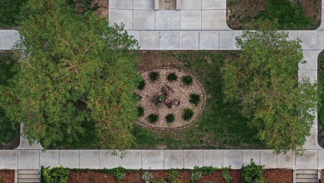 Aerial view of the landscaped grounds at Cherry Creek featuring lush green trees, concrete walkways, and a central circular garden bed in Denver, Colorado, United States.