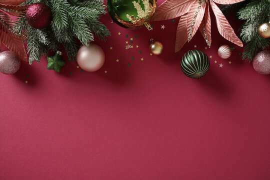 Christmas baubles and fir branches on burgundy background