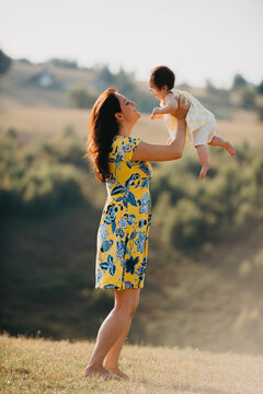 Mother Lifting Baby Daughter Outdoors in Sunny Field &mdash; Family Love, Joy and Summer Bonding