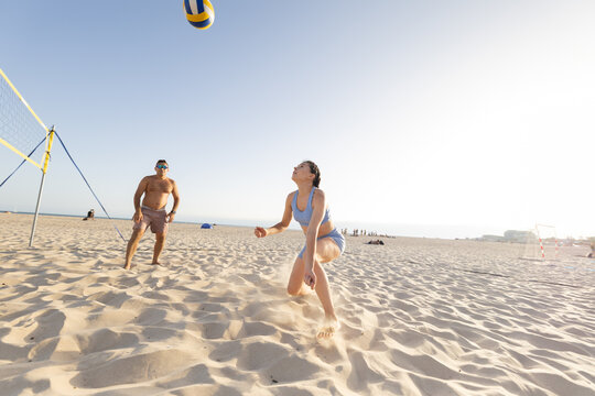 People playing beach volleyball on sandy beach