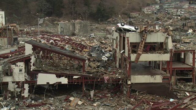 Car Rests On Building In Destroyed Town In Aftermath Of Tsunami In Japan
