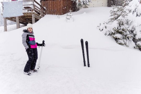 Woman skier enjoying a snowy winter day at a mountain resort, standing with ski poles in deep fresh snow surrounded by snow covered fir trees, alpine landscape, outdoor recreation