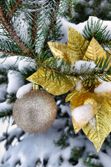 A tree is decorated with a gold ornament and golden leaves while snow covers the branches. The scene shows winter spirit for New Year and Christmas moments © Anoo