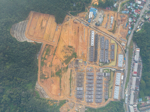 Aerial view of a large residential construction housing development with rows of new houses, earthworks, and surrounding forest in Bukit Mertajam, Penang, Malaysia.