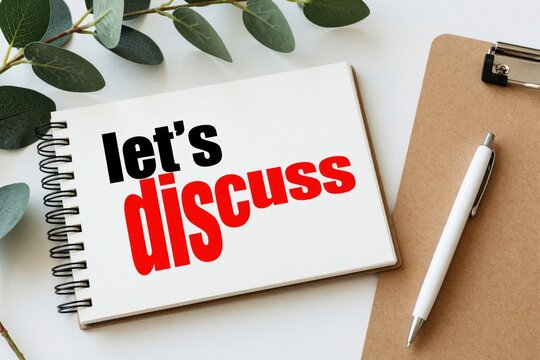 Open spiral notebook with lets discuss text on white paper. Green eucalyptus leaves, white pen, brown clipboard on desk. Concept for business meeting, brainstorming session, teamwork, communication,