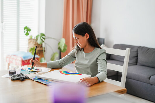 Female kid painting a rainbow at school - Education, homework, back to school, art and creativity for children concept - Main focus on face - UGC content