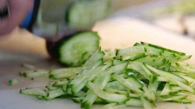 Chef rapidly julienning fresh green cucumber slices into thin strips for professional salad preparation julienne slicing chopping vegetable kitchen julienne slicing chopping vegetable kitchen
