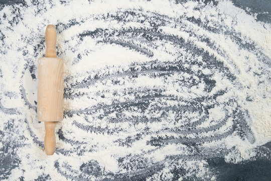 Background with flour and wooden rolling pin, baking cookies, biscuits, cake or pastry for christmas holiday, homemade pizza, receipe ingredients, preparation of food