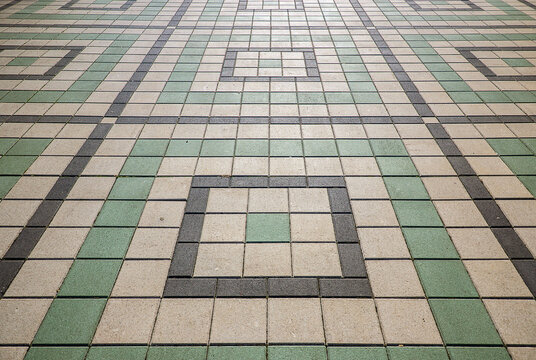 Tiled outdoor pavement of public city square with green and grey geometric square patterns and lines with copy space