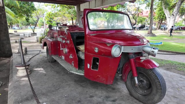Vintage red three-wheeled fire truck parked under shelter