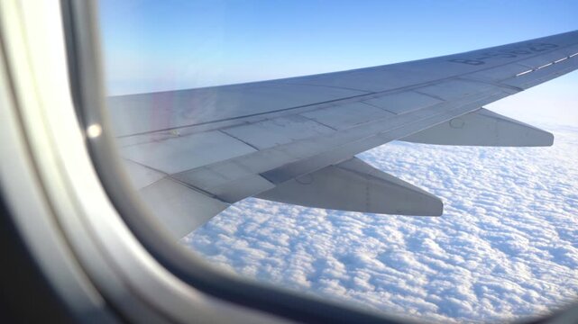 Airplane Wing Viewed Through Cabin Window Above Cloudy Sky