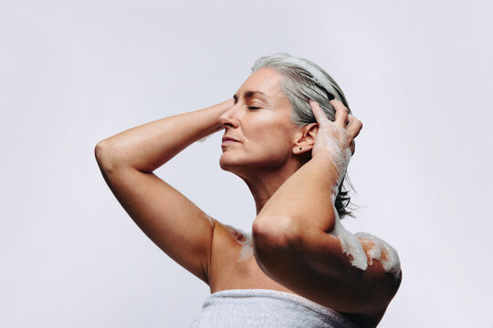 Mature woman massaging shampoo into wet hair