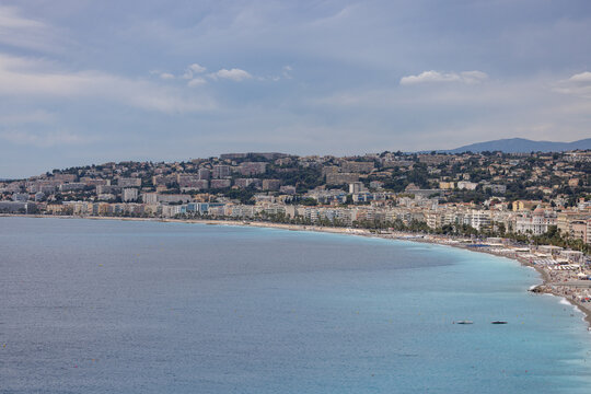 Aerial view of the Baie des Anges and coastline of Nice, featuring turquoise Mediterranean Sea, Promenade des Anglais, and urban architecture in Nice, Provence-Alpes-Cote d'Azur, France.