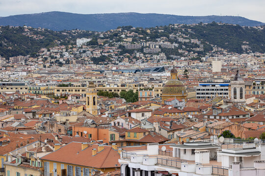 Aerial view of historic rooftops, church domes, and dense urban architecture of Vieux Nice, with surrounding hills and Mediterranean cityscape in Nice, Provence-Alpes-Cote d'Azur, France.