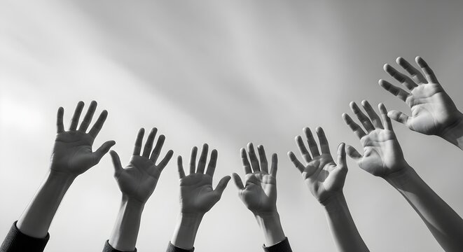 Diverse Hands Raised in Unity monochrome low angle view of multiple open palms reaching towards a bright sky ideal for community outreach campaigns and perfect for social justice or human rights.