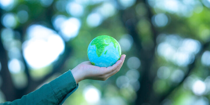 A businessperson holding a globe symbolizes environmental responsibility, a sustainable future, eco-friendliness, ecosystem conservation, renewable resources, and sustainable development.