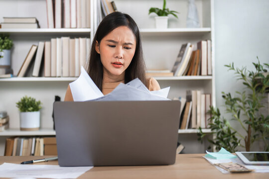 Woman stares at papers, looking stressed and frustrated