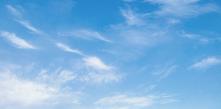 Soft white clouds drift across a vast, clear blue sky