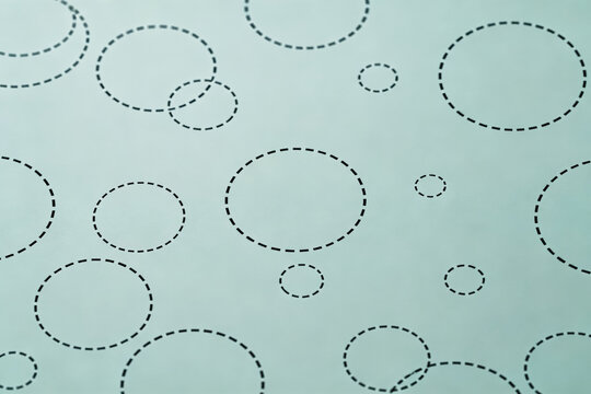 A minimal graphic pattern of various dashed circles arranged on a pale light background surface.
