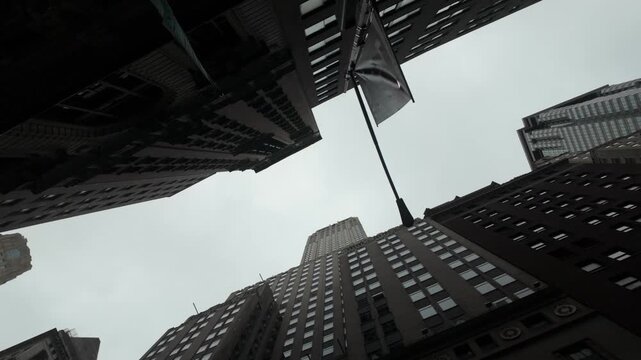 Looking up at towering skyscrapers in new york city's financial district on a cloudy day, capturing the powerful economy and corporate world of the stock market